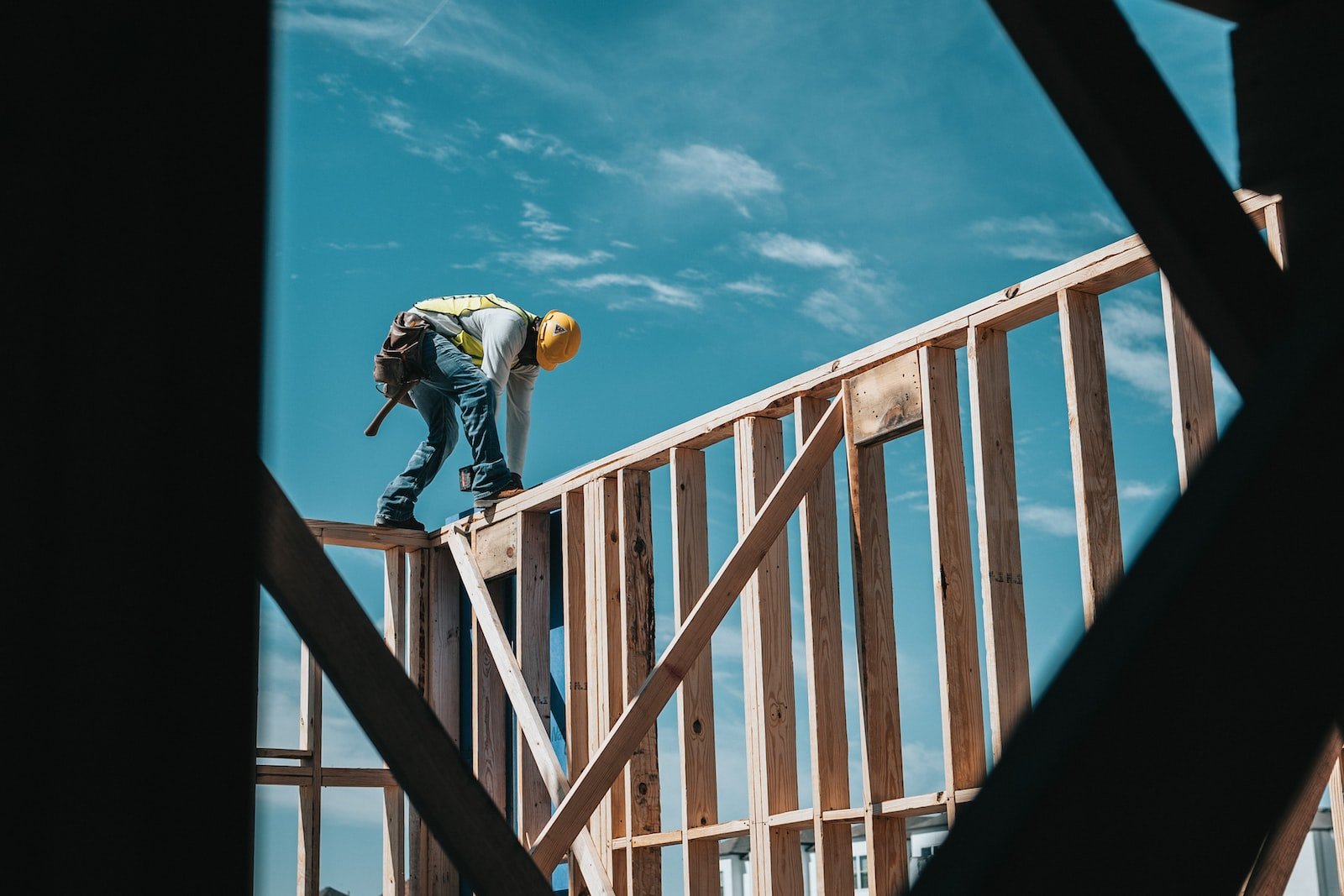 Photo by Josh Olalde man in yellow shirt and blue denim jeans jumping on brown wooden railings under blue and
